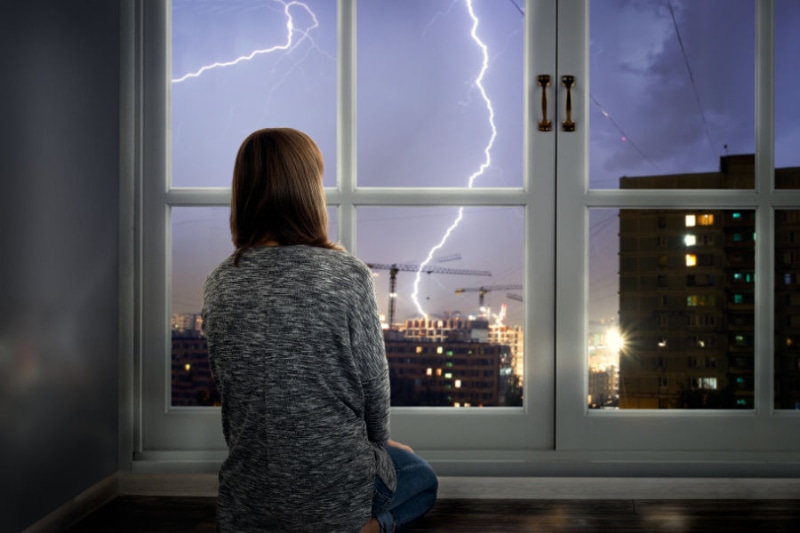 How to Protect Your AC From Storms - Girl Looking Outside.