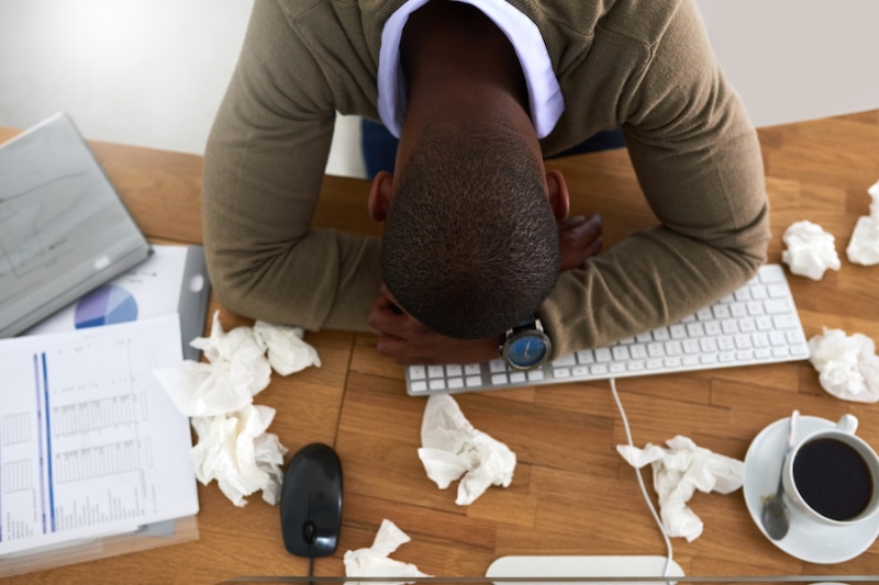 Man with allergies laying his head on the desk.